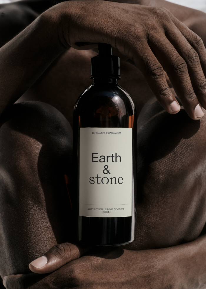 Elegant product mockup featuring a hand holding an Earth & Stone body lotion bottle, ideal for beauty brand presentations.